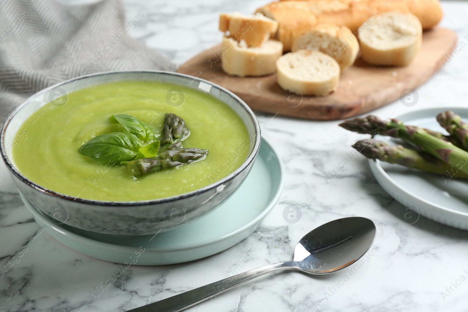 Photo of Delicious asparagus soup served on white marble table