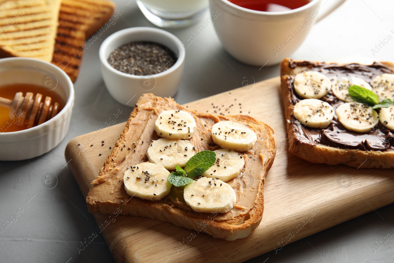 Photo of Tasty toasts with banana, mint and chia seeds on wooden board