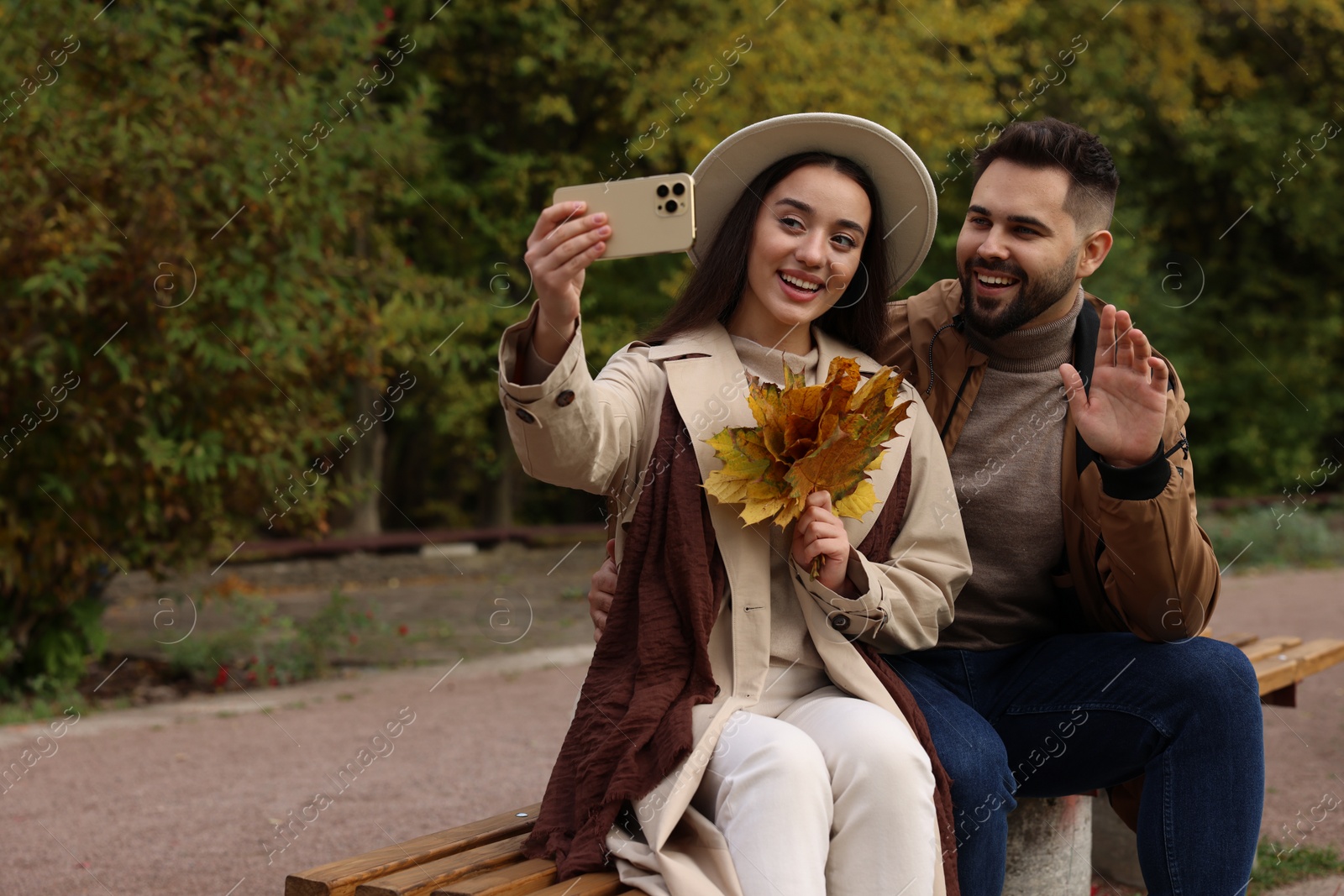 Photo of Happy young couple taking selfie in autumn park, space for text