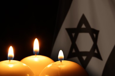 Image of Burning candles against flag of Israel on black background
