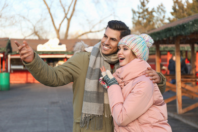 Photo of Happy couple in warm clothes at winter fair. Christmas season