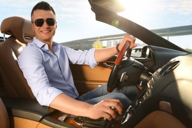 Photo of Businessman driving luxury convertible car outdoors on sunny day