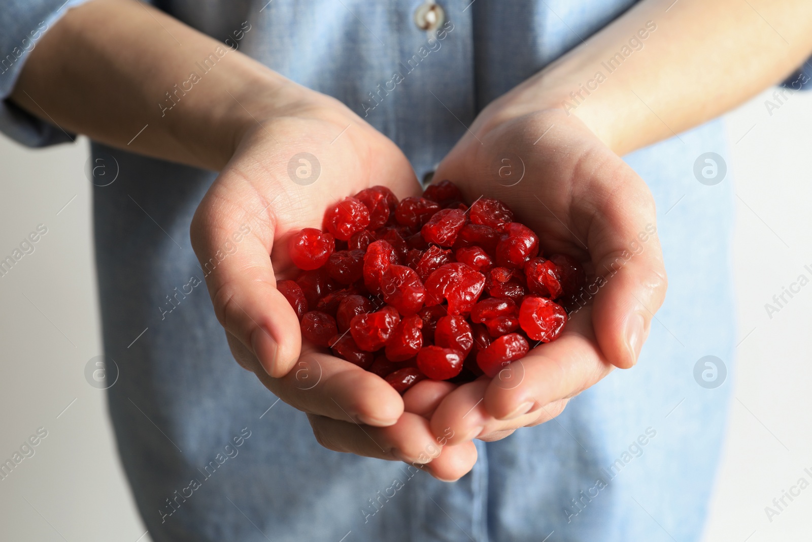Photo of Woman holding handful of tasty cherries on light background, closeup. Dried fruits as healthy food