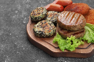 Photo of Different tasty vegan meat products and lettuce on grey table, closeup. Space for text