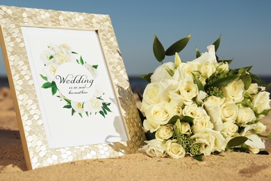 Photo of Wedding invitation and beautiful bouquet on sandy beach, closeup