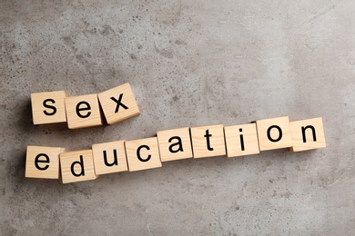 Photo of Wooden blocks with phrase "SEX EDUCATION" on stone background, flat lay