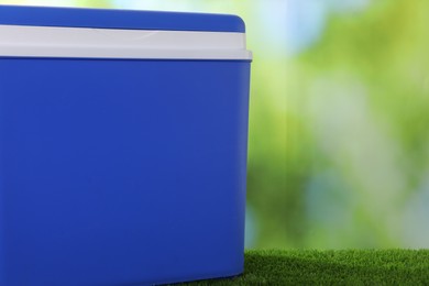 Photo of One plastic cool box on artificial grass, closeup. Space for text