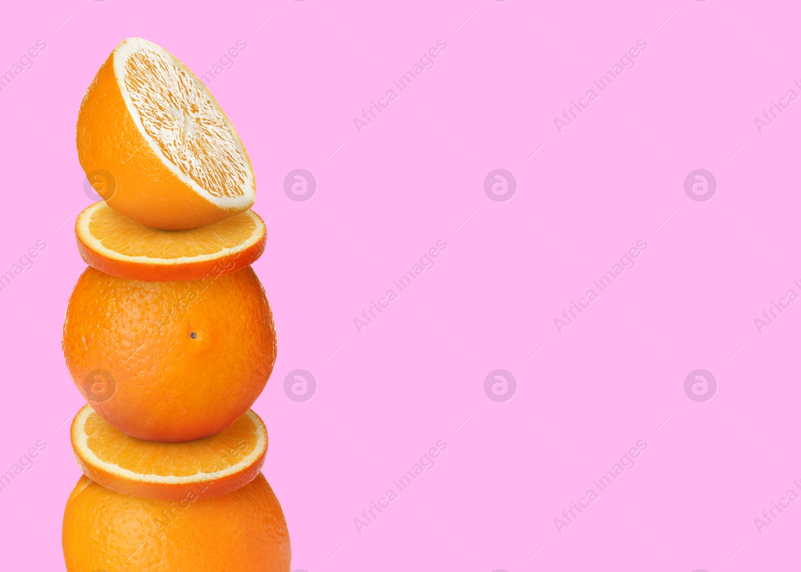 Image of Stacked cut and whole oranges on pink yellow background, space for text