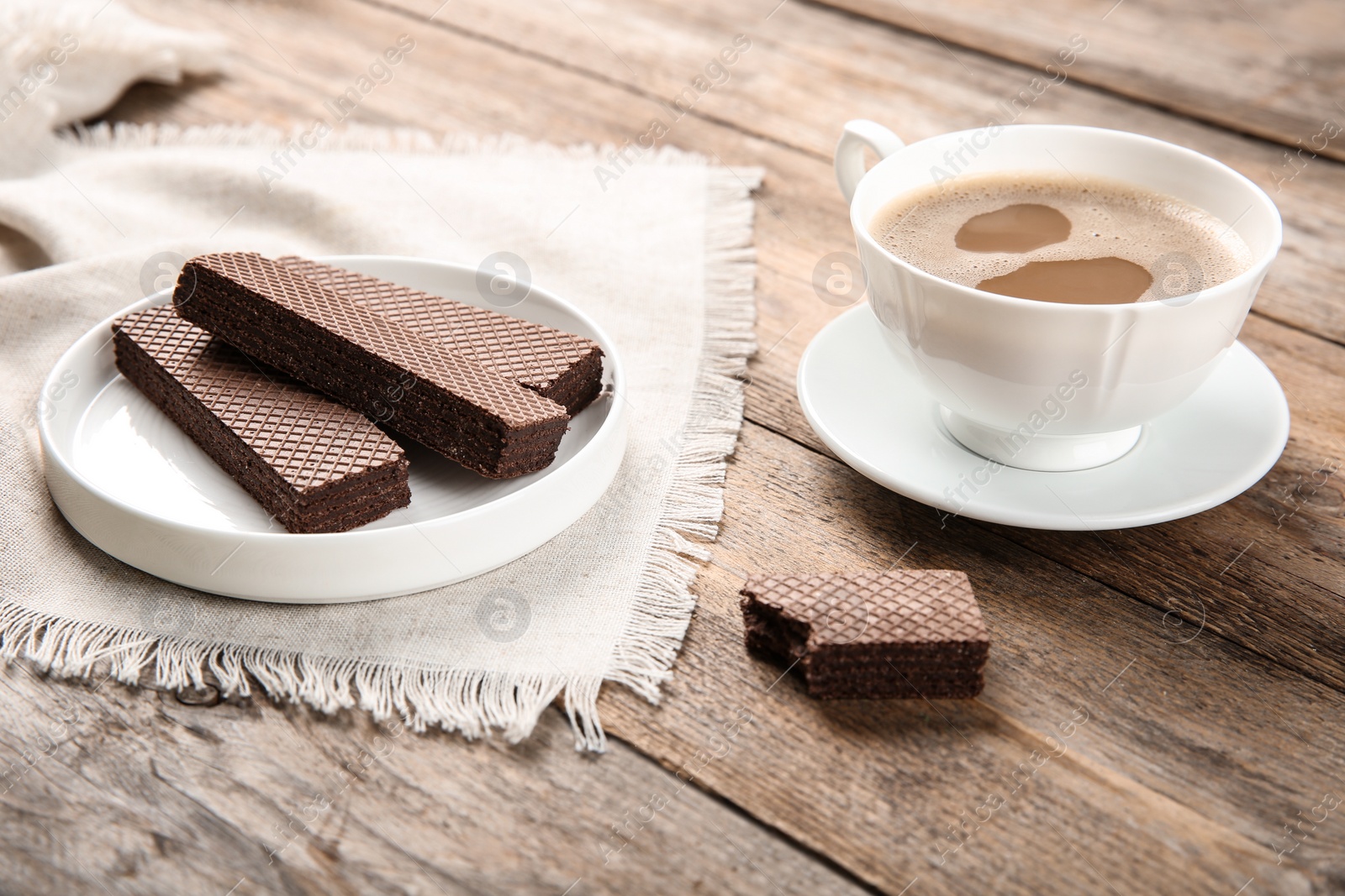 Photo of Plate of delicious chocolate wafers with cup of coffee on brown wooden background