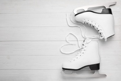 Pair of ice skates on white wooden background, top view. Space for text