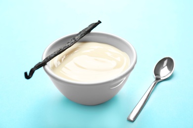 Photo of Bowl with vanilla pudding and sticks on color background