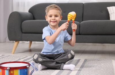 Little boy playing toy maracas at home