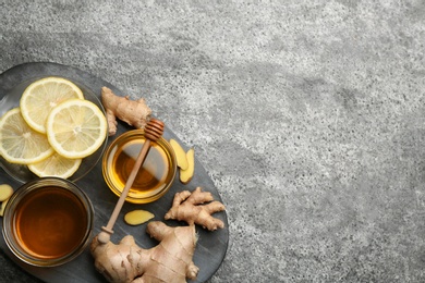 Photo of Ginger and other natural cold remedies on grey table, top view. Space for text