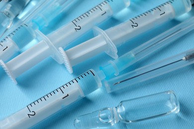 Disposable syringes with needles and ampules on light blue background, above view