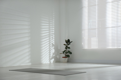 Photo of Unrolled grey yoga mat on floor in room. Space for text