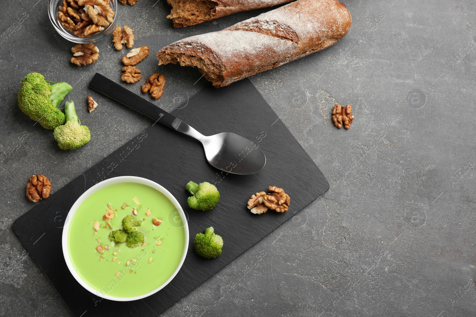 Photo of Flat lay composition with bowl of broccoli cream soup on grey table, space for text