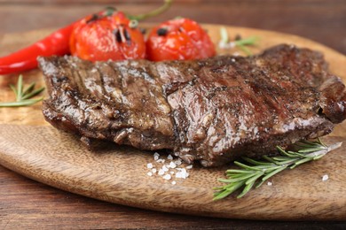 Photo of Delicious roasted beef meat, vegetables and spices on wooden table, closeup