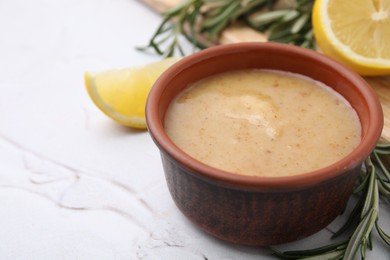 Delicious turkey gravy, rosemary and lemon on white table, closeup. Space for text