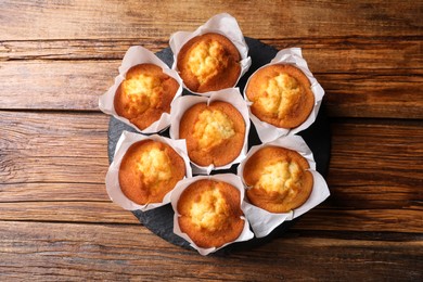 Photo of Delicious sweet muffins on wooden table, top view