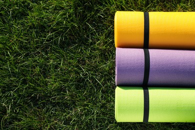 Photo of Bright exercise mats on fresh green grass outdoors, flat lay. Space for text