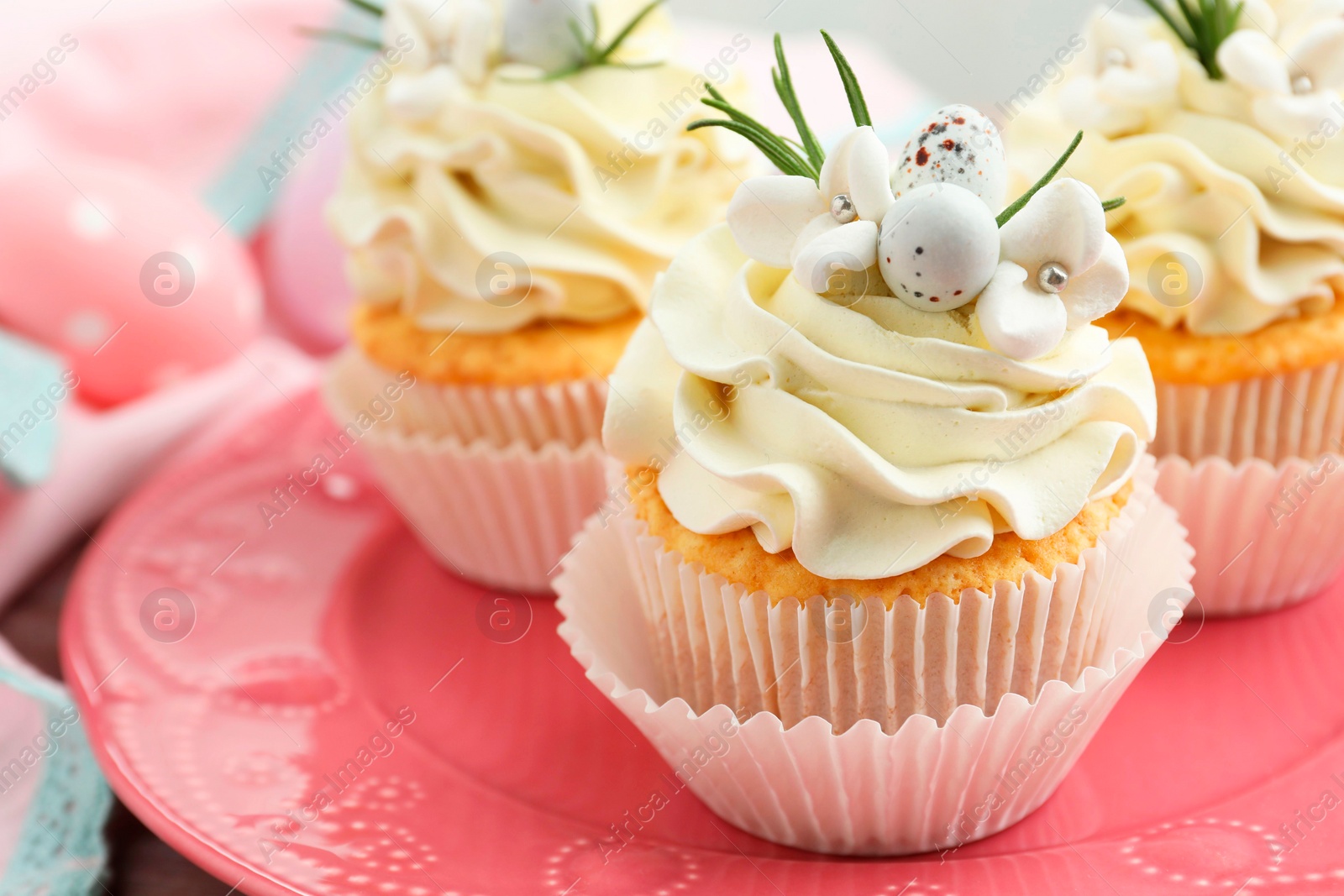 Photo of Tasty Easter cupcakes with vanilla cream on table, closeup