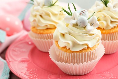 Photo of Tasty Easter cupcakes with vanilla cream on table, closeup