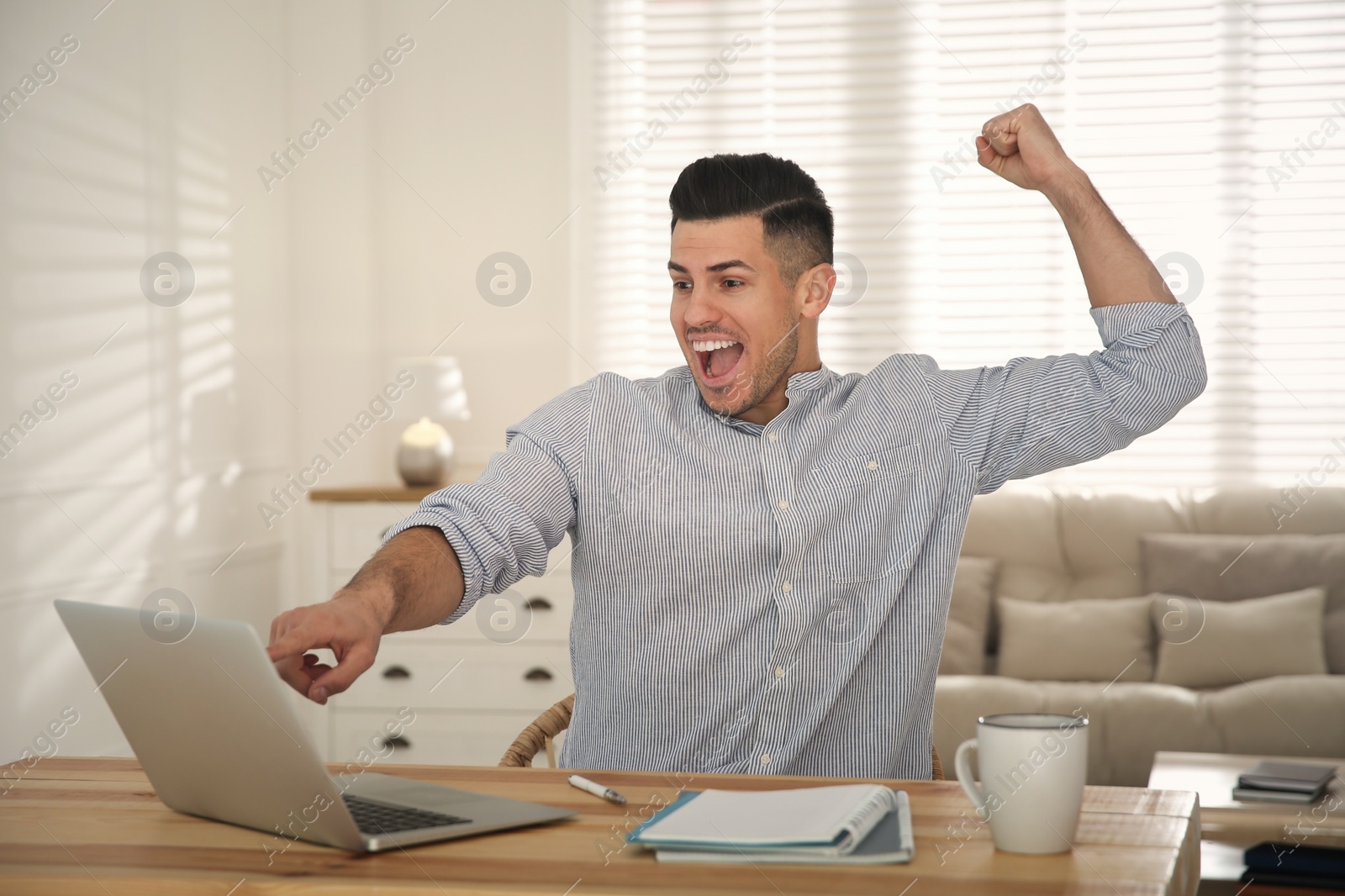 Photo of Emotional man participating in online auction using laptop at home