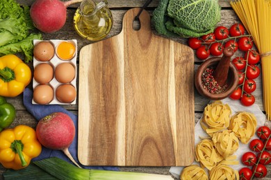 Photo of Board surrounded by different ingredients on wooden table, flat lay with space for text. Cooking classes