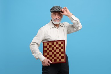 Photo of Man with chessboard on light blue background