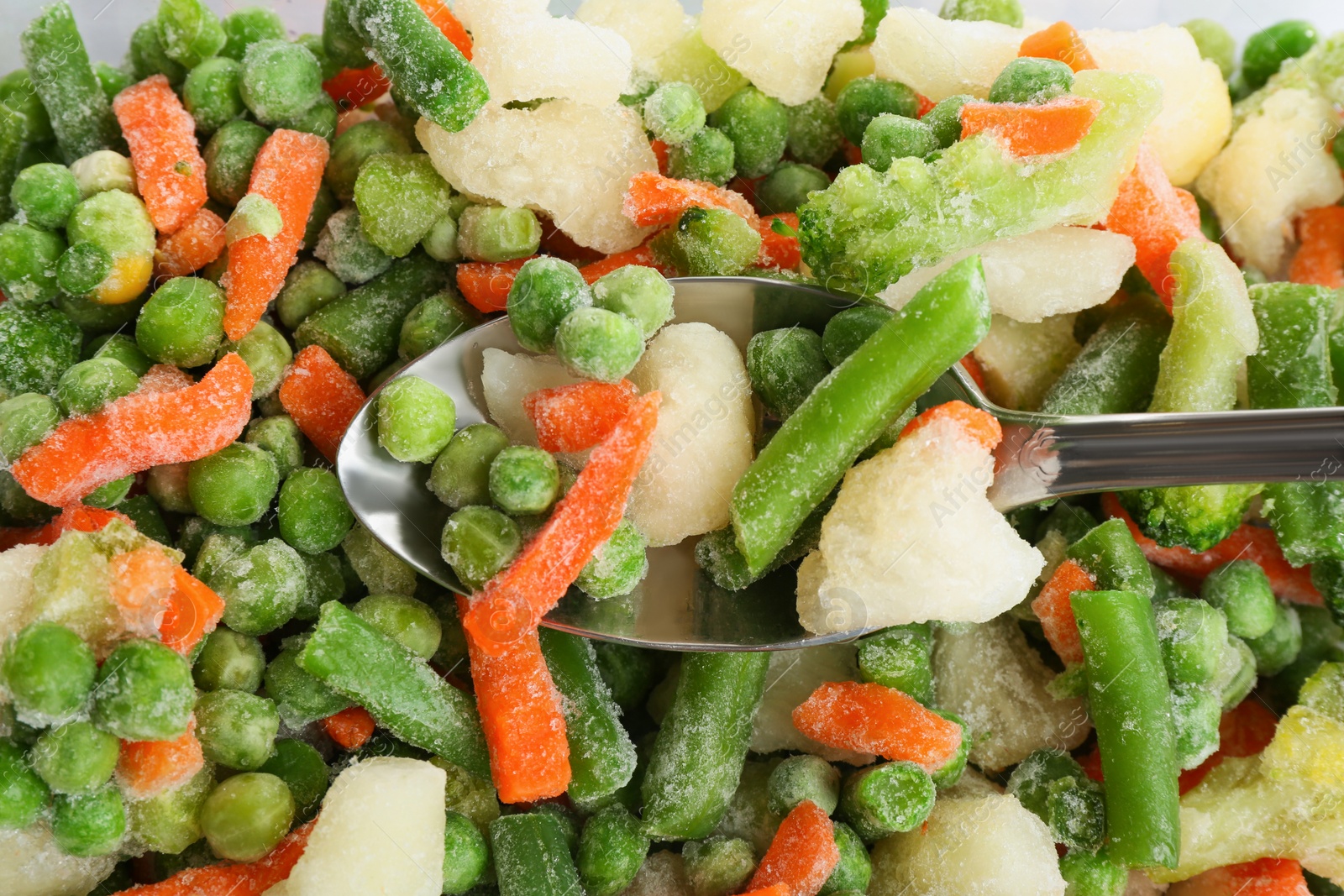 Photo of Mix of frozen vegetables and spoon, closeup