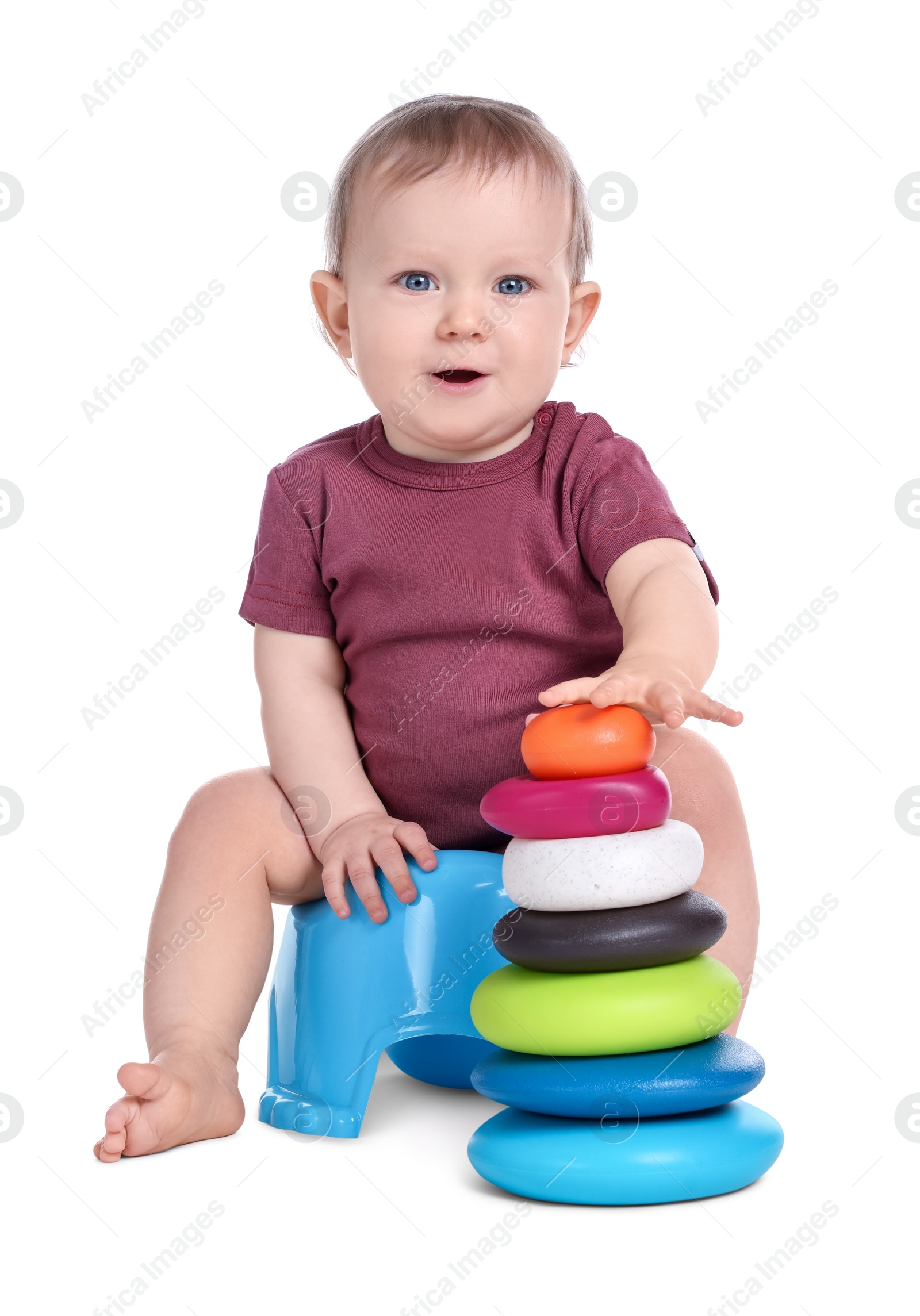 Photo of Little child with toy pyramid sitting on baby potty against white background