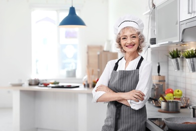 Photo of Professional female chef standing near table in kitchen