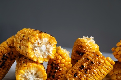 Photo of Grilled corn cobs on table against gray background, closeup