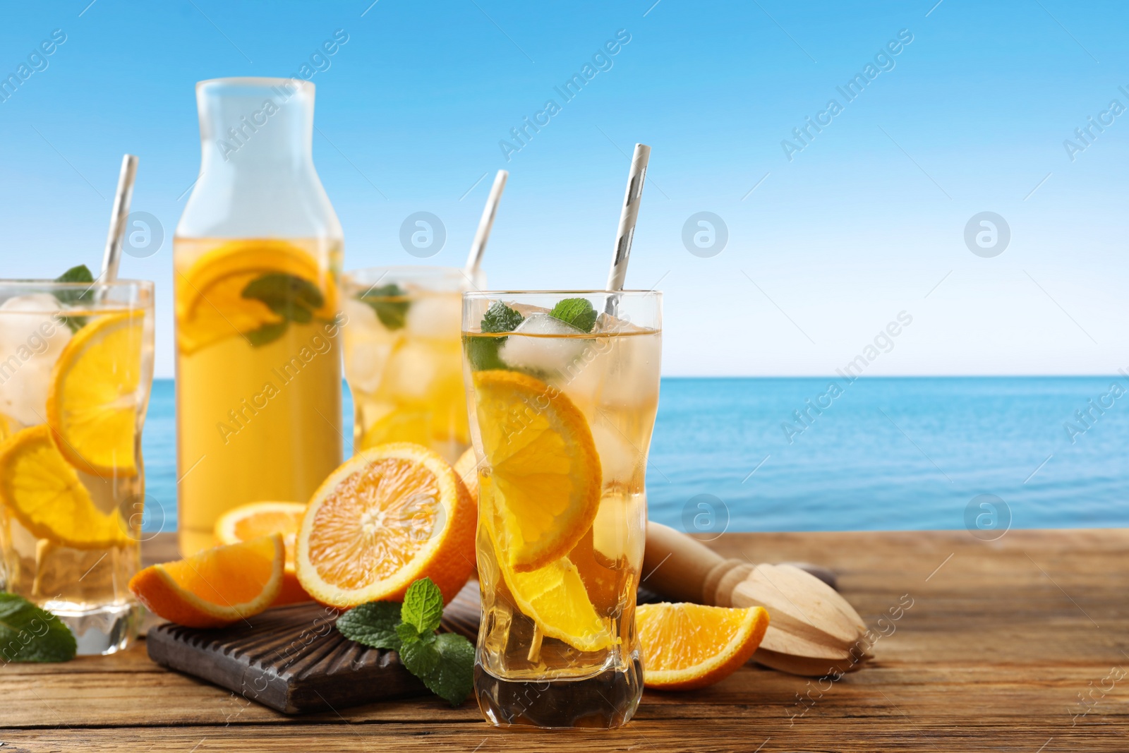 Image of Tasty refreshing drink on wooden table against sea