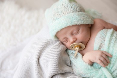 Photo of Cute newborn baby in warm hat sleeping on plaid, above view