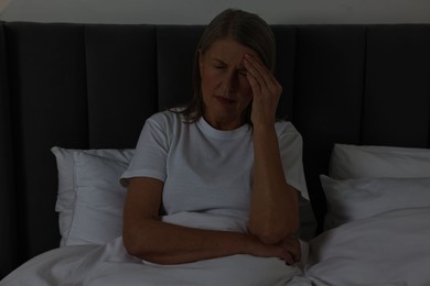 Woman suffering from headache in bed at night