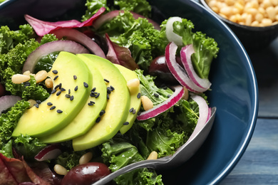 Photo of Tasty fresh kale salad on blue wooden table, closeup