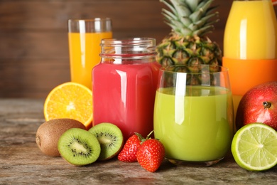 Photo of Glassware with different juices and fresh fruits on wooden background