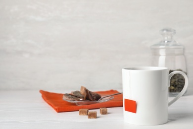 Photo of Cup of hot fresh tea and brown sugar on table against light background. Space for text