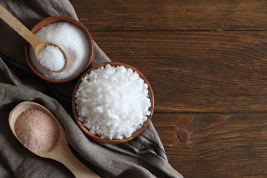 Photo of Different types of organic salt on wooden table, flat lay. Space for text