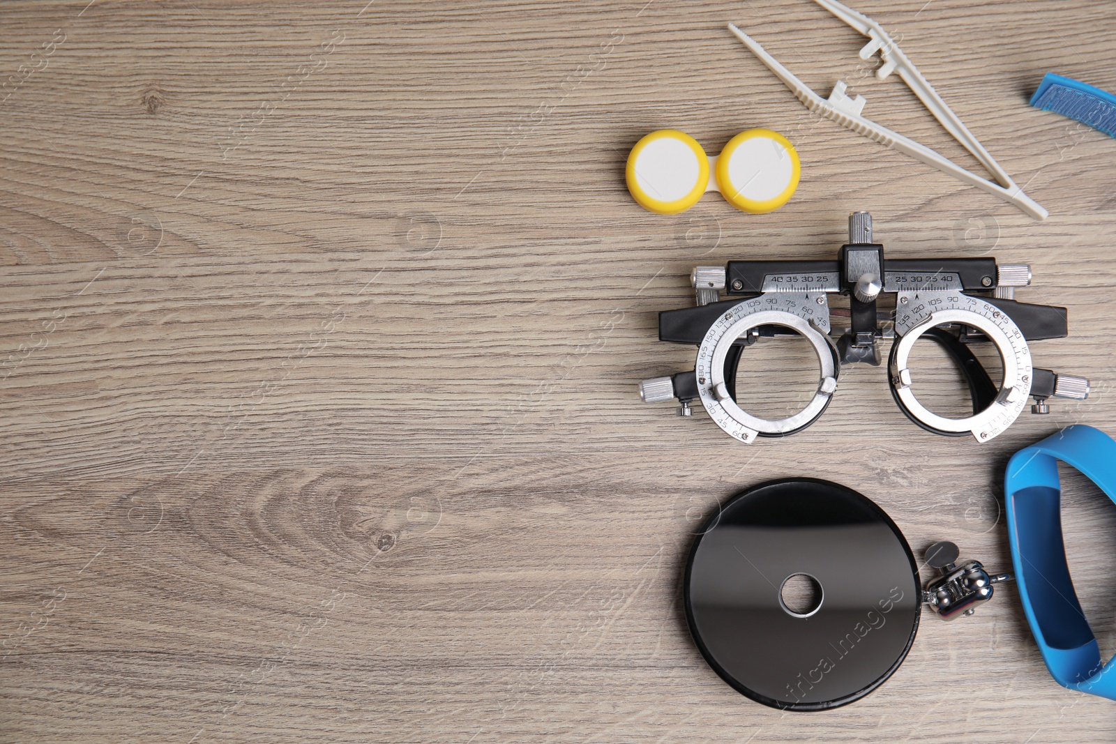 Photo of Different ophthalmologist tools on wooden background, flat lay. Space for text