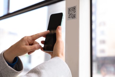 Photo of Woman scanning QR code with her smartphone in public transport, closeup