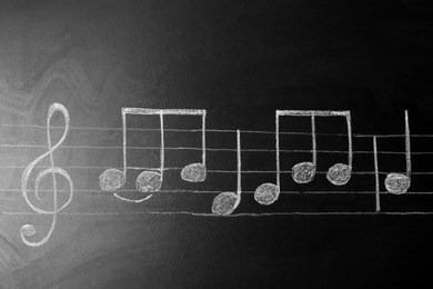 Music scale with treble clef and notes on chalkboard, top view