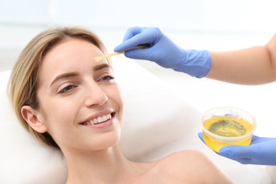 Photo of Beautiful woman getting wax epilation of face in salon