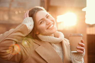 Young woman with cup of coffee on city street in morning