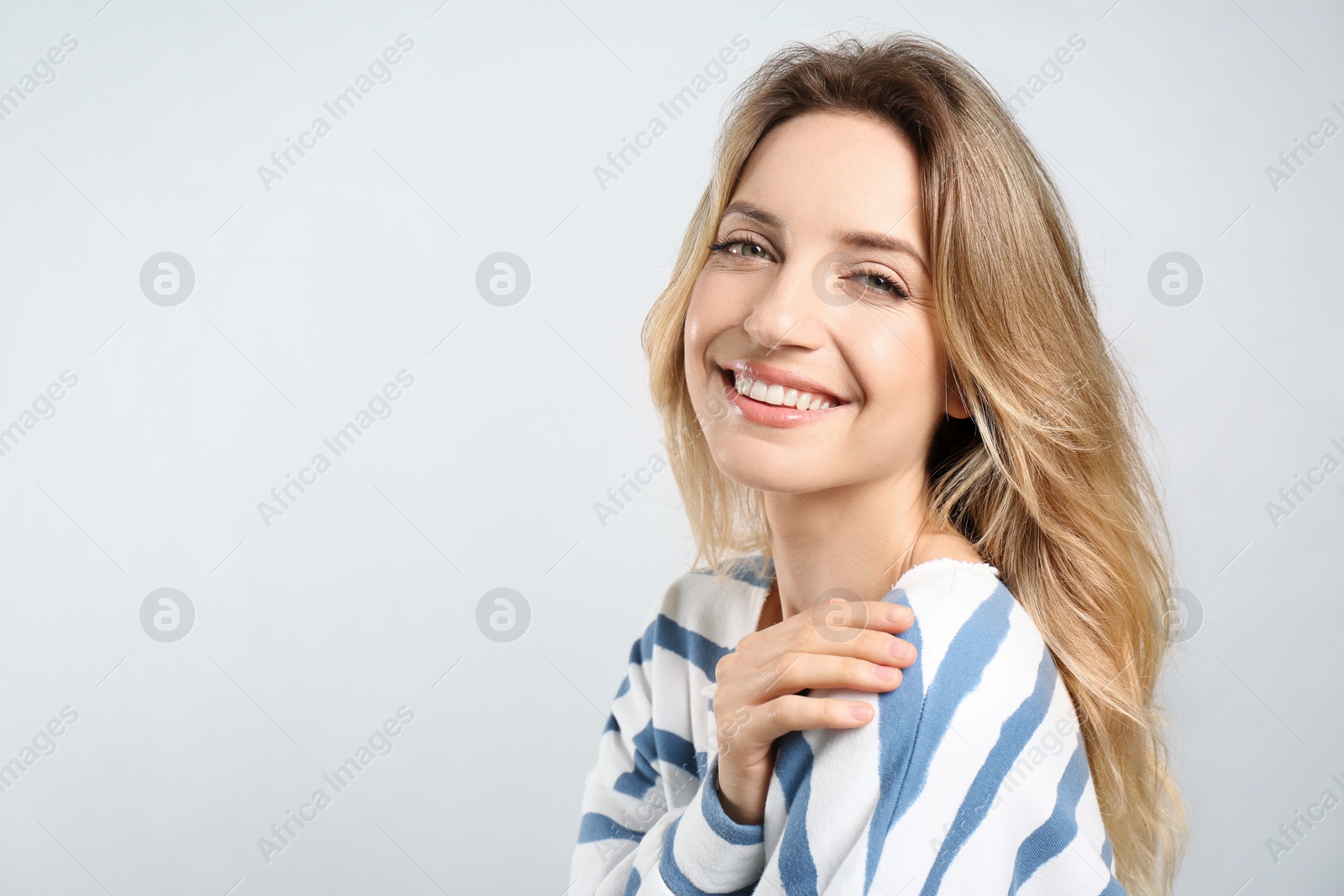 Photo of Portrait of happy young woman with beautiful blonde hair and charming smile on light background. Space for text