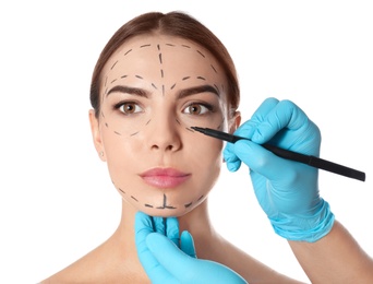 Photo of Doctor drawing marks on woman's face for cosmetic surgery operation against white background