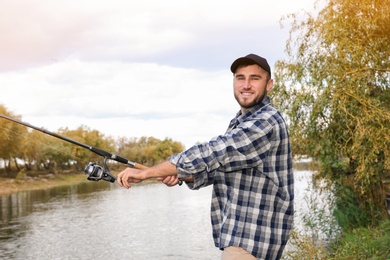 Photo of Man with rod fishing at riverside. Recreational activity