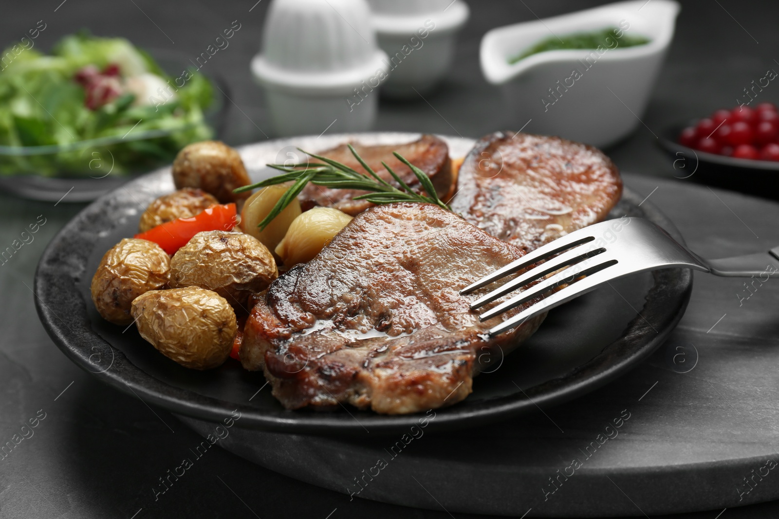 Photo of Tasty beef tongue pieces, rosemary and potatoes on grey table, closeup