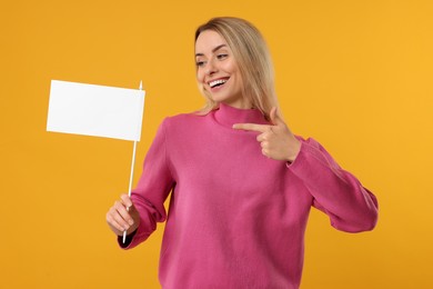 Photo of Happy woman pointing at blank white flag on orange background. Mockup for design